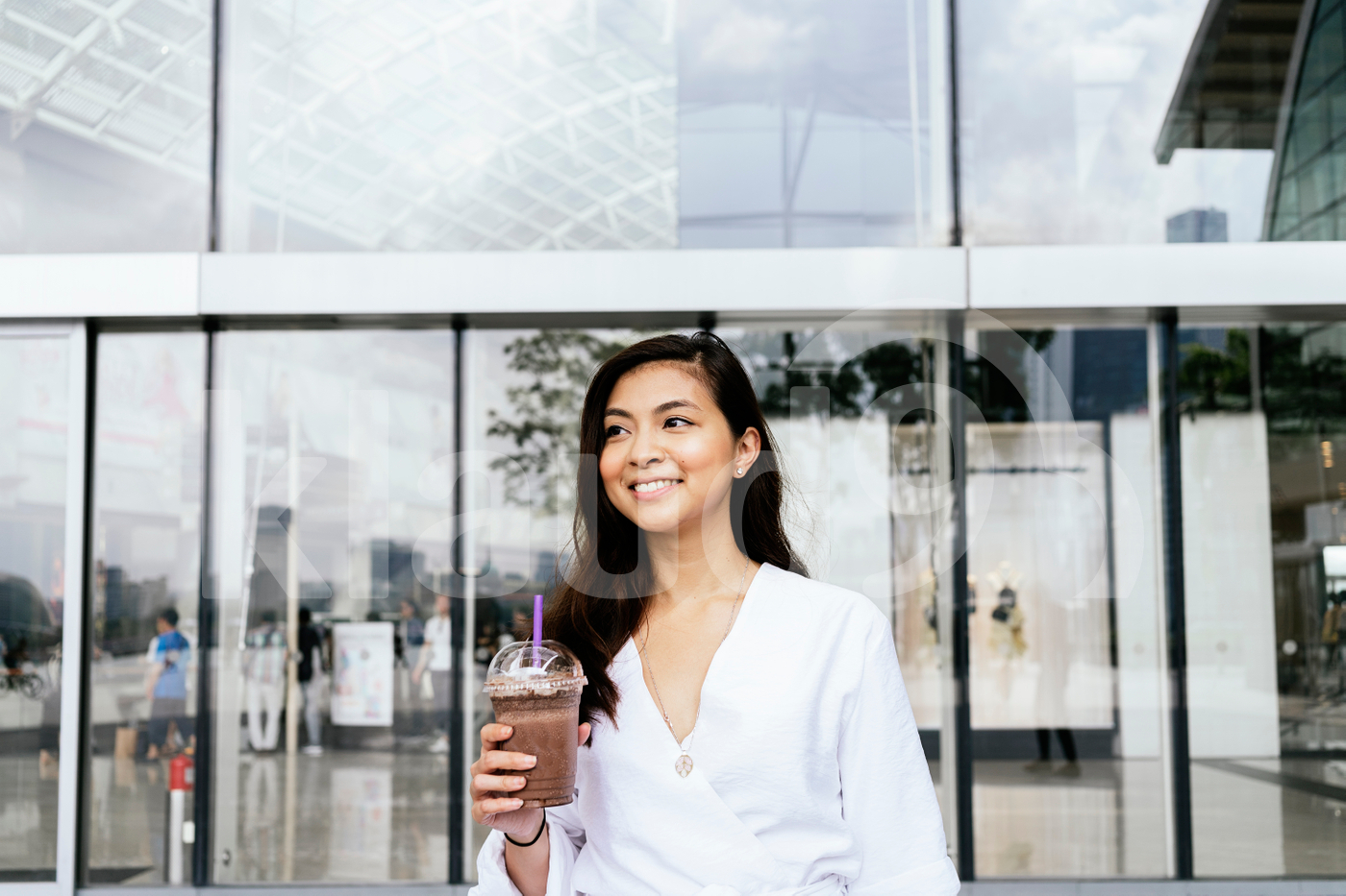 Young adult Asian woman standing in the mall holding drink cup
