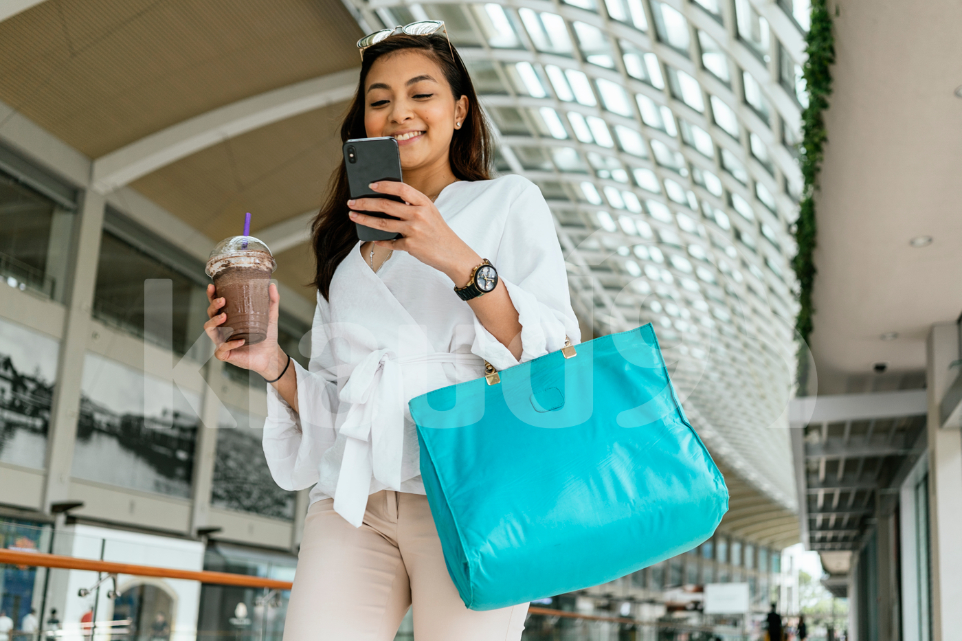 Woman walking down the mall while using mobile