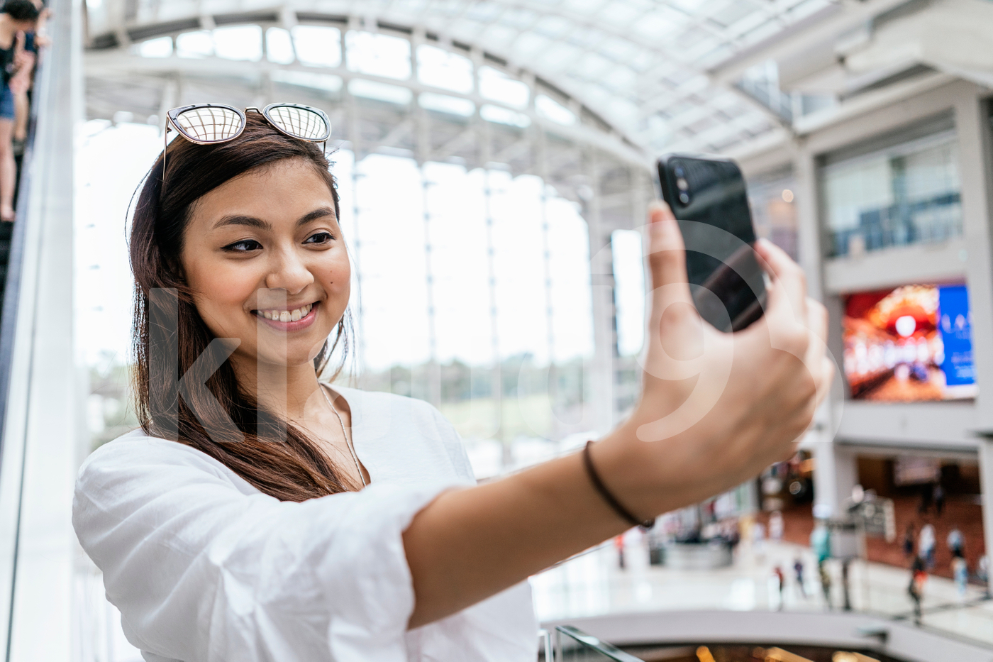 Asian woman posing for a selfie in a mall