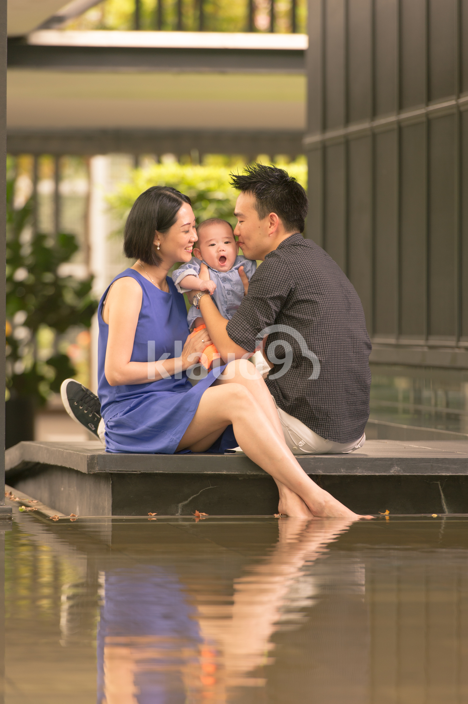 Chinese Dad and Mom kissing baby.