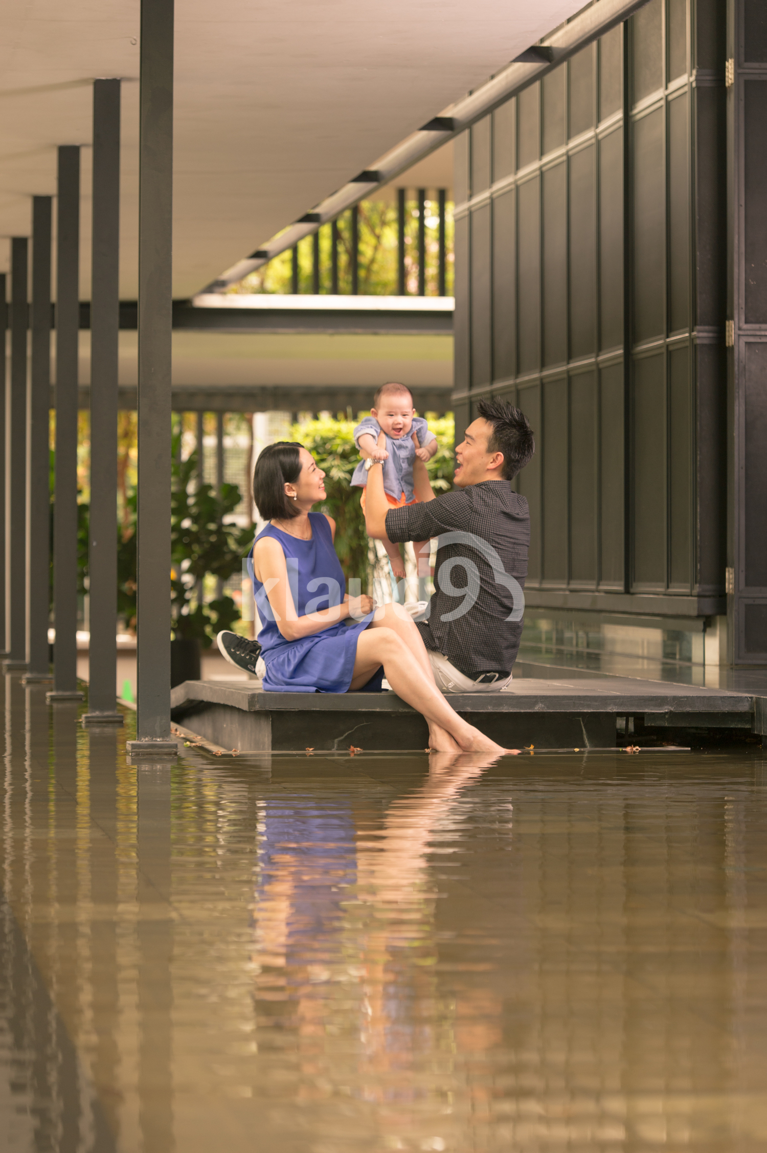 Young Chinese Father carrying his Baby with Mother looking on