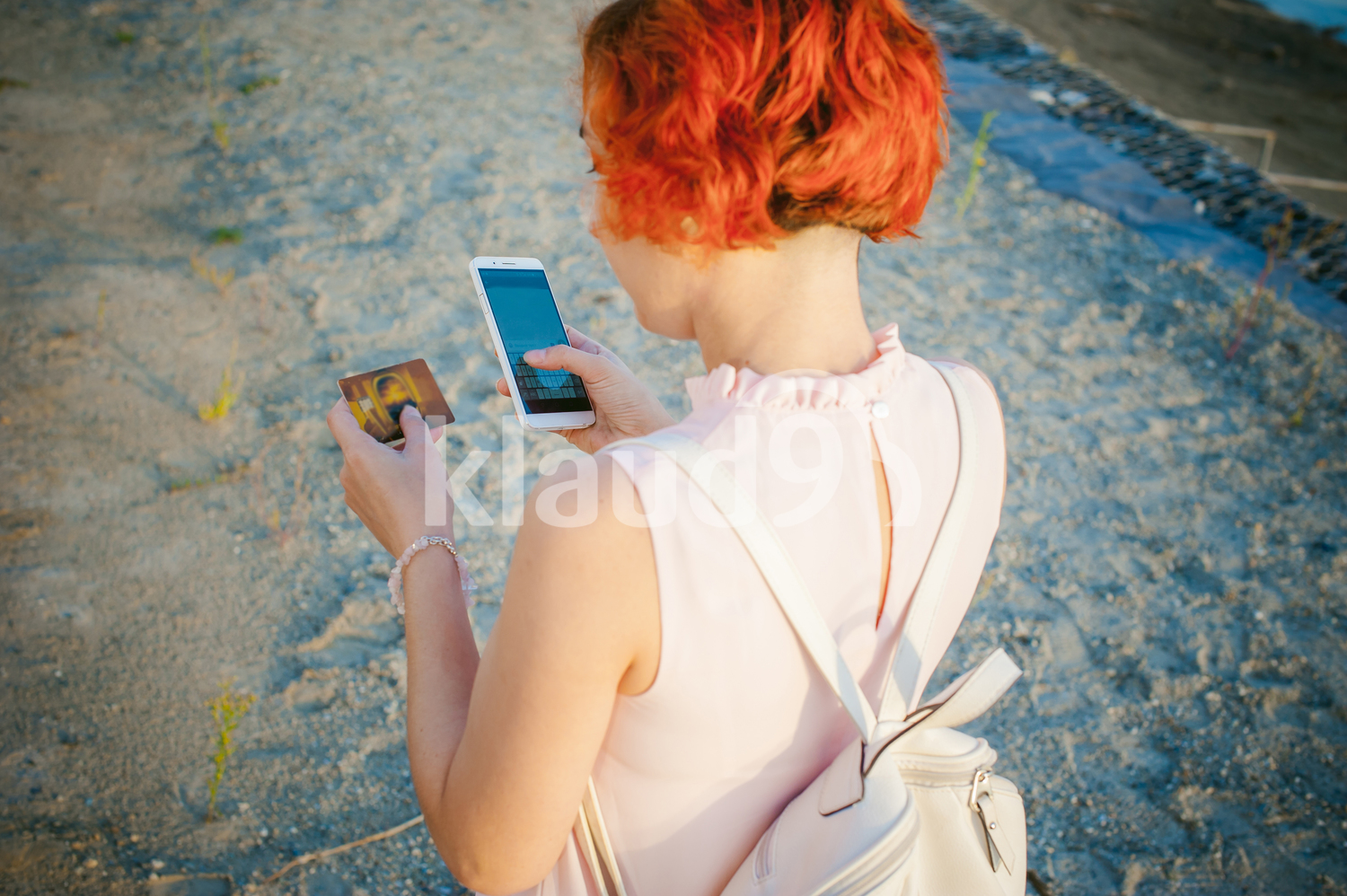 girl with red hair walking by the river at sunset making online payments
