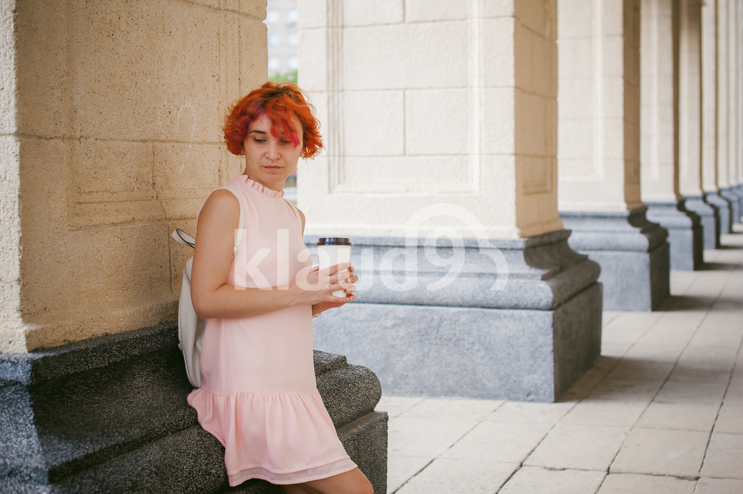 Portrait of a red haired woman resting on building column