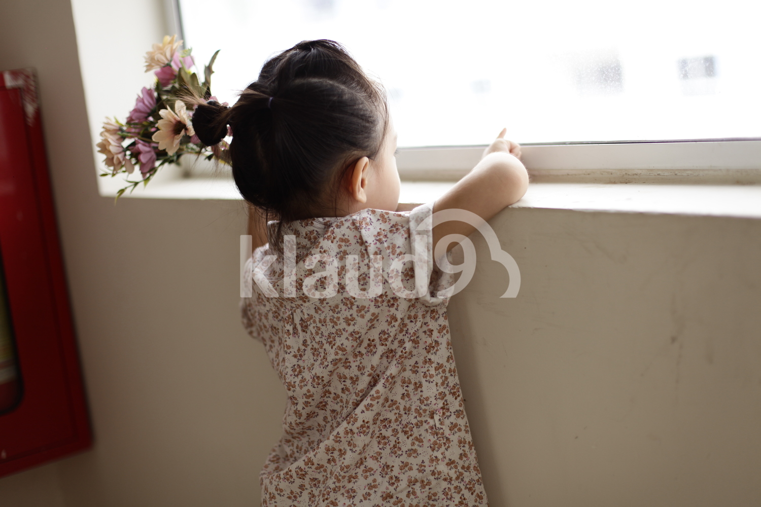 Backview of pretty little girl holding a bunch of colourful flowers in her hands