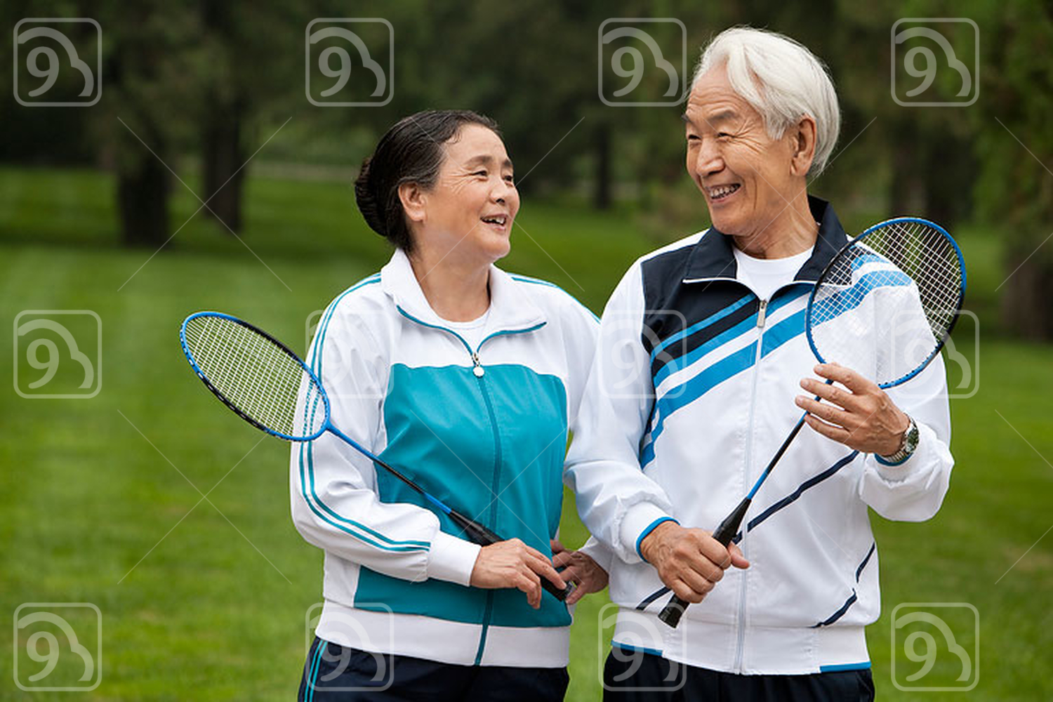 Senior Chinese couple holding badminton rackets in a park 