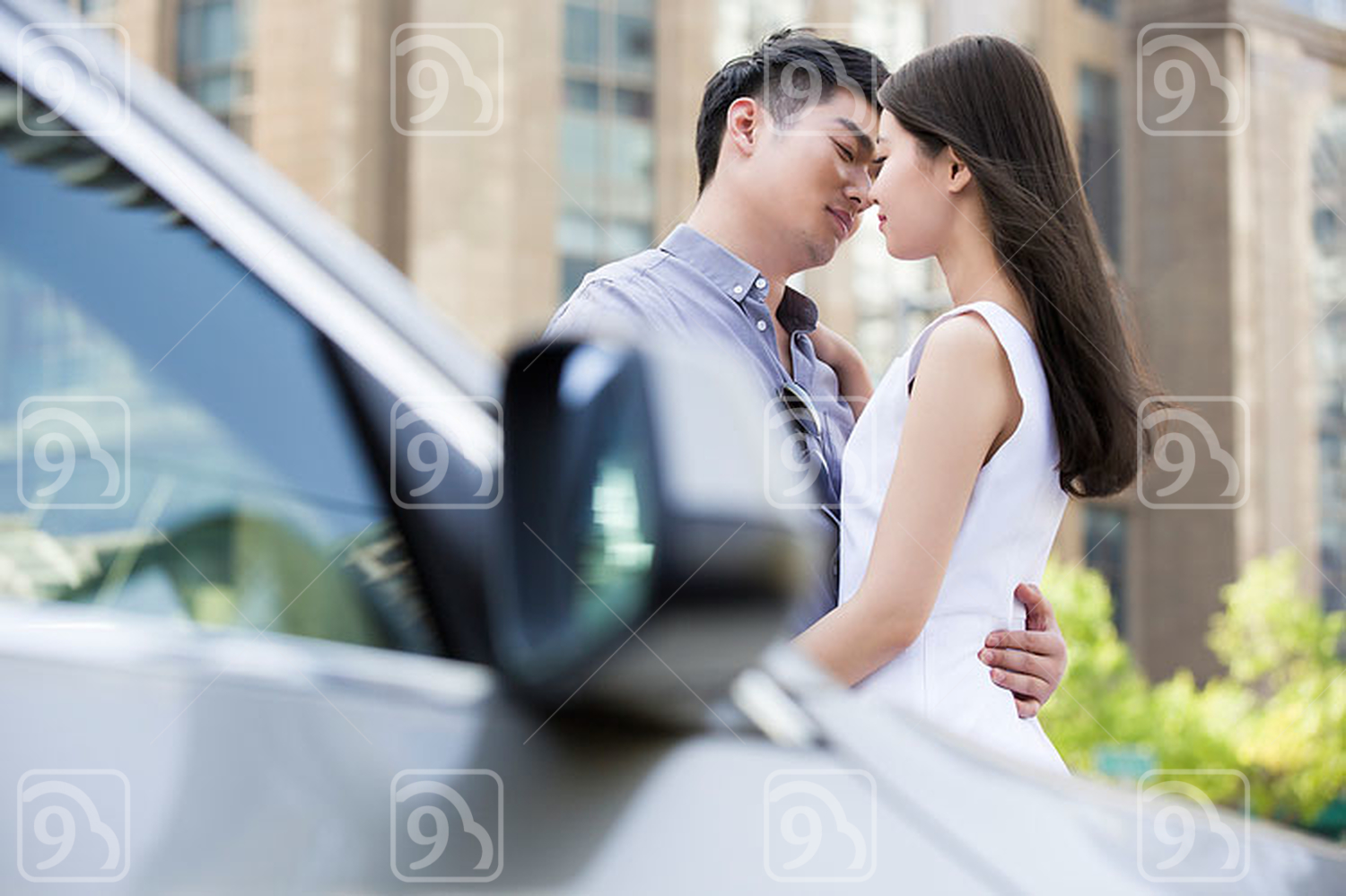 Young Chinese couple kissing next to their car 