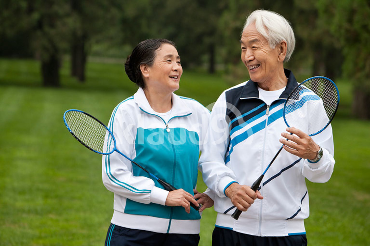 Senior Chinese couple holding badminton rackets in a park