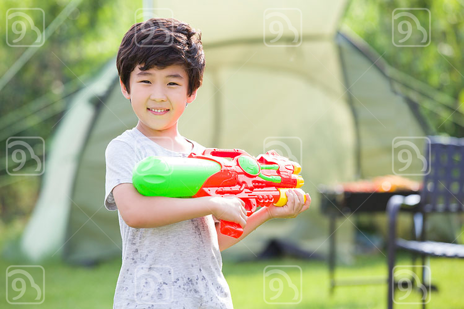 Happy Chinese boy holding a squirt gun 