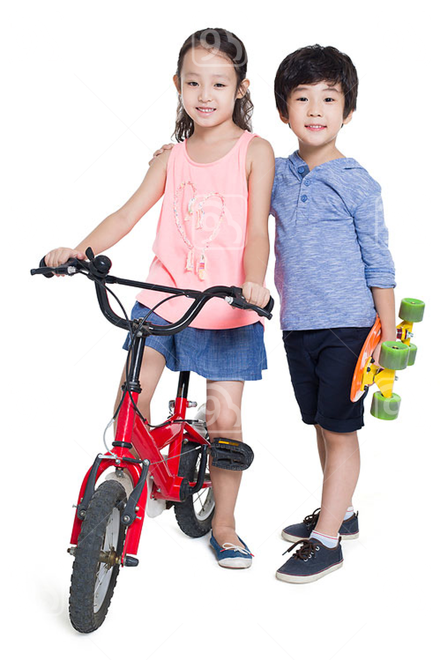 Little Chinese girl riding bike and boy holding a skateboard 