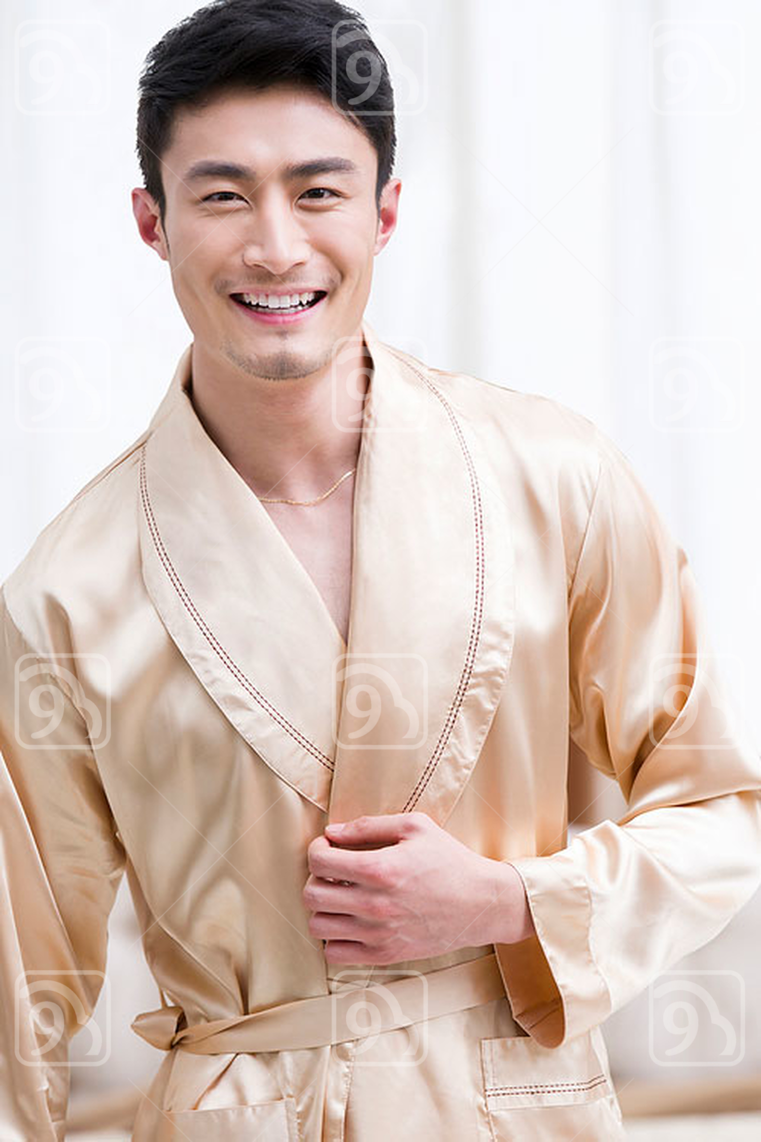 Cheerful young Chinese man in bedroom 