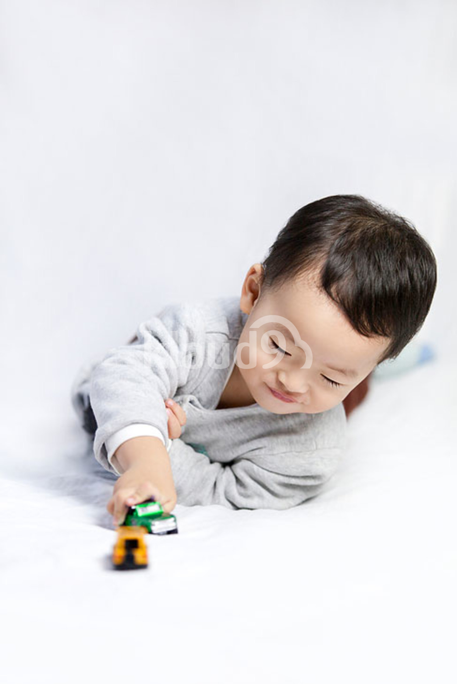 Happy little Chinese boy playing toy car