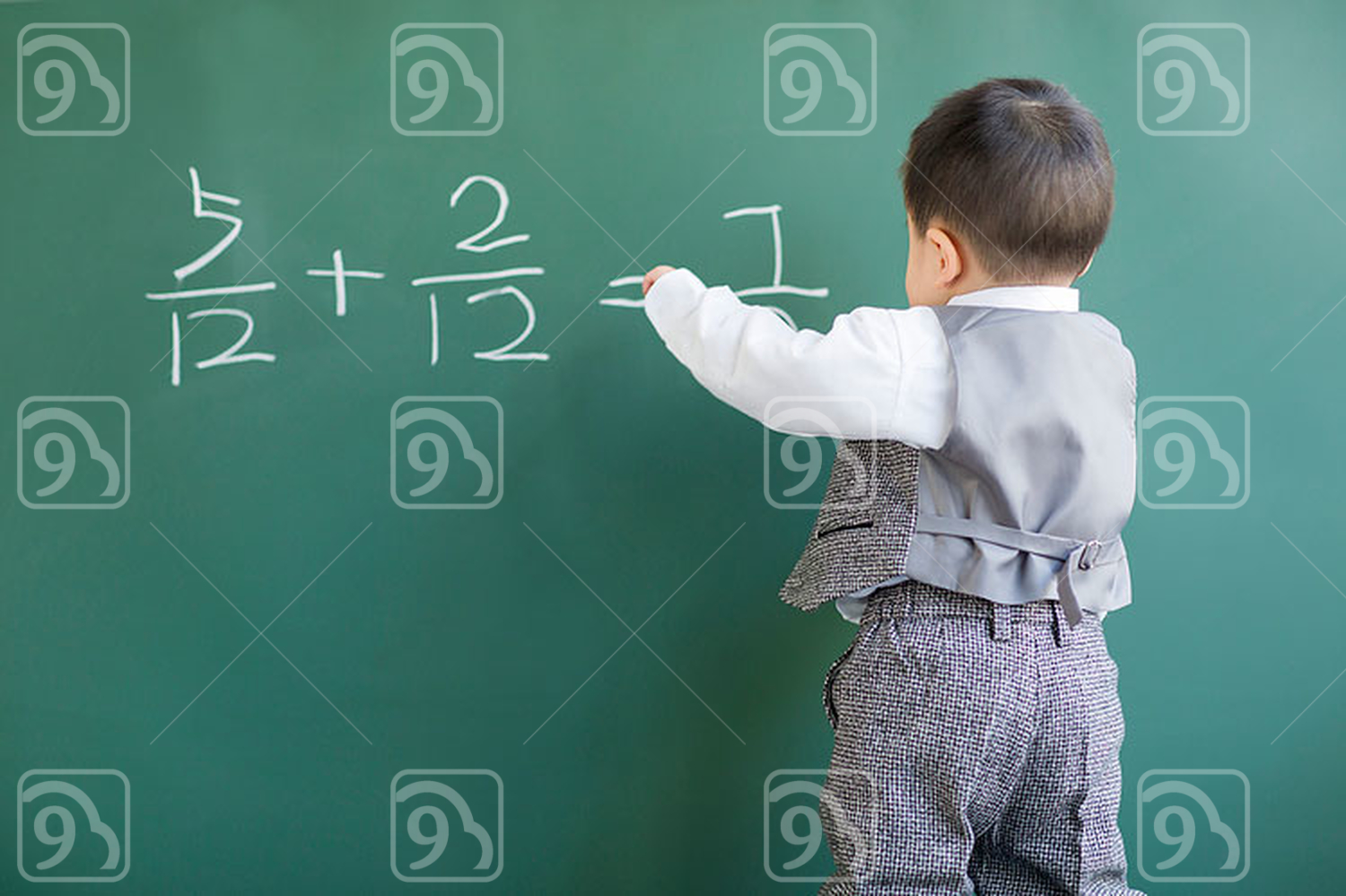 Cute Chinese baby doing mathematics on blackboard 