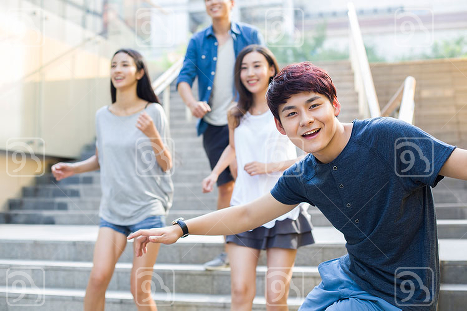 Young Chinese man sliding down banister on steps 