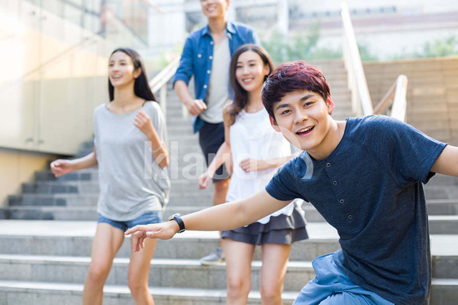 Young Chinese man sliding down banister on steps