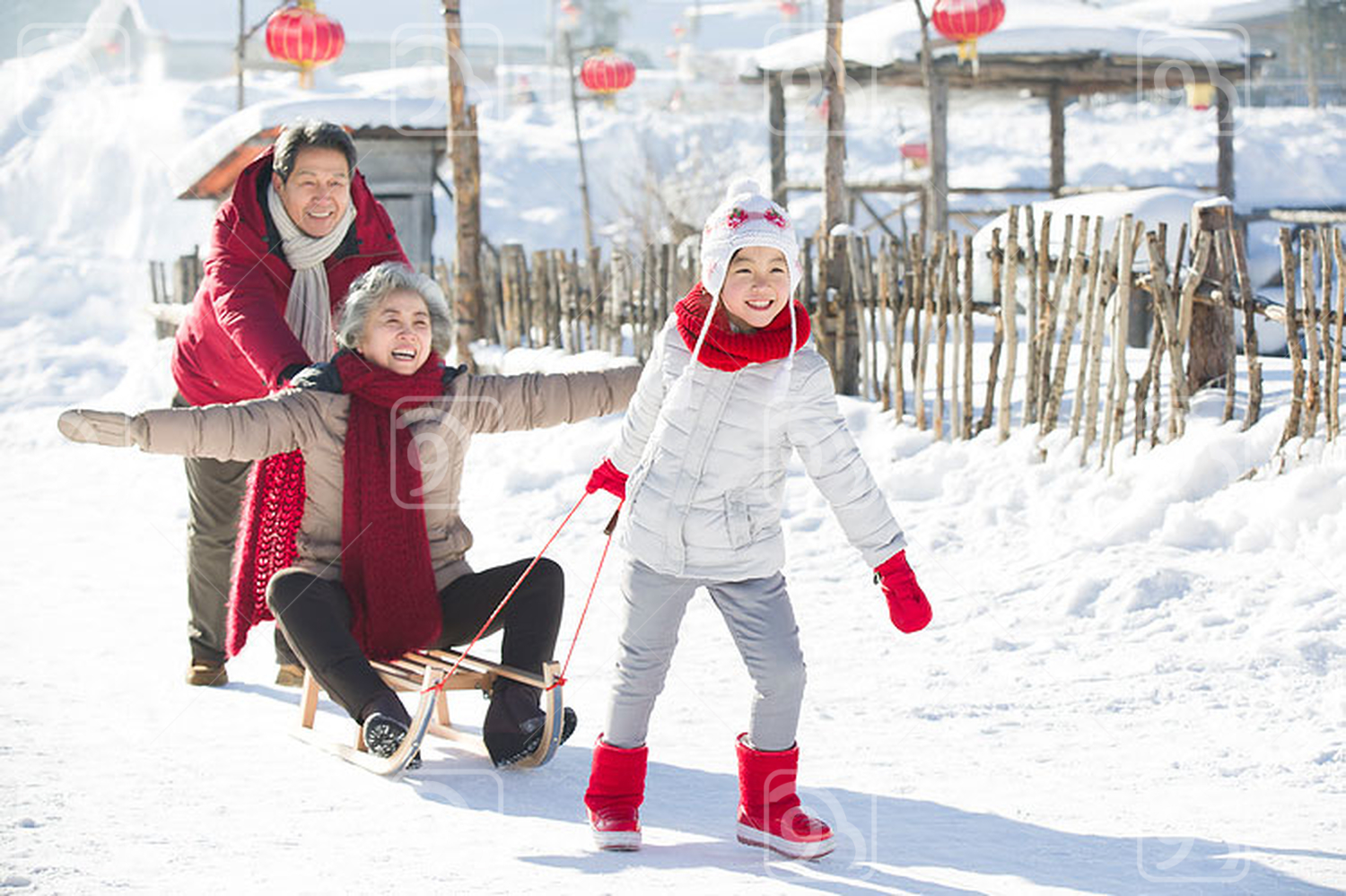 Happy Chinese family playing with sled in the snow 