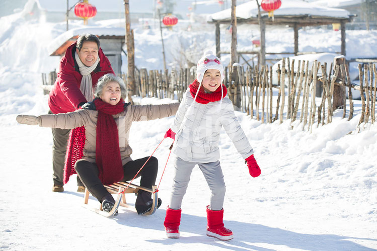 Happy Chinese family playing with sled in the snow