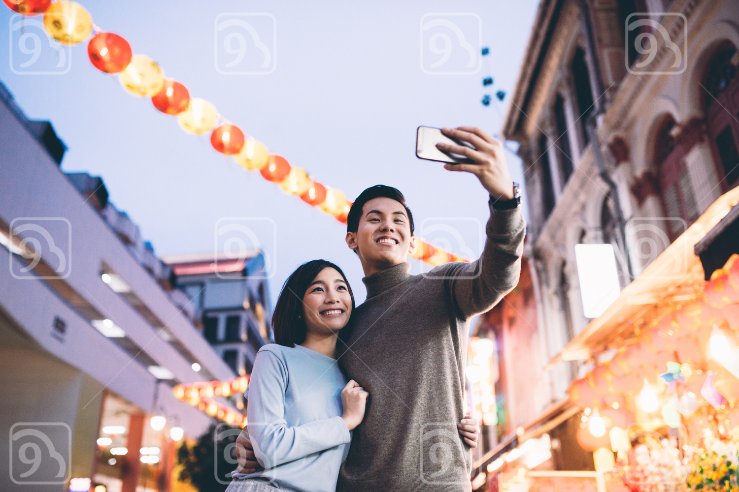 Young couple doing a selfie in Chinatown, Singapore during dusk 