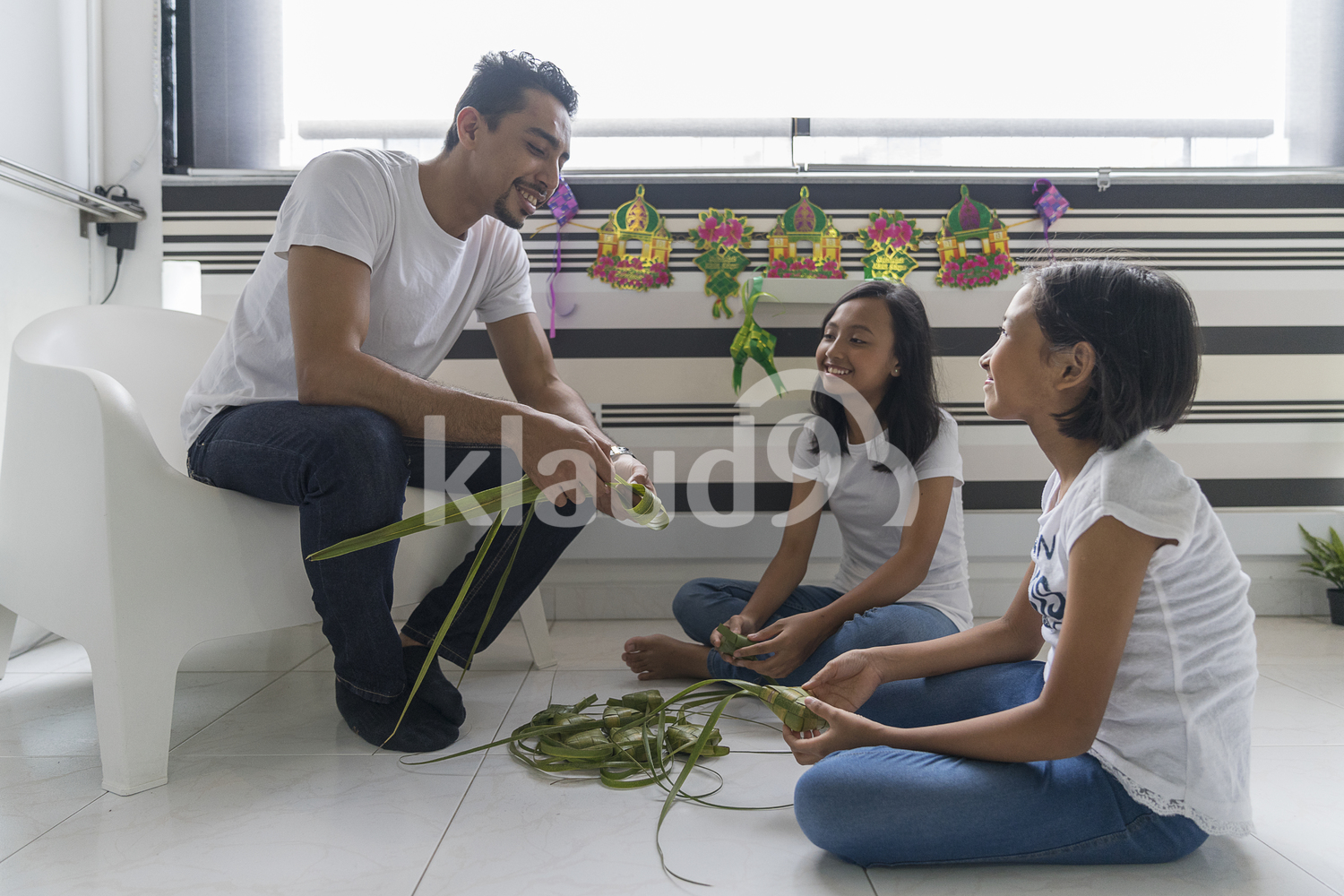 Father teaching his kids how to make ketupat.