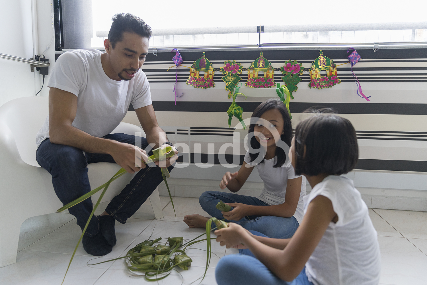 Father teaching his kids how to make ketupat.