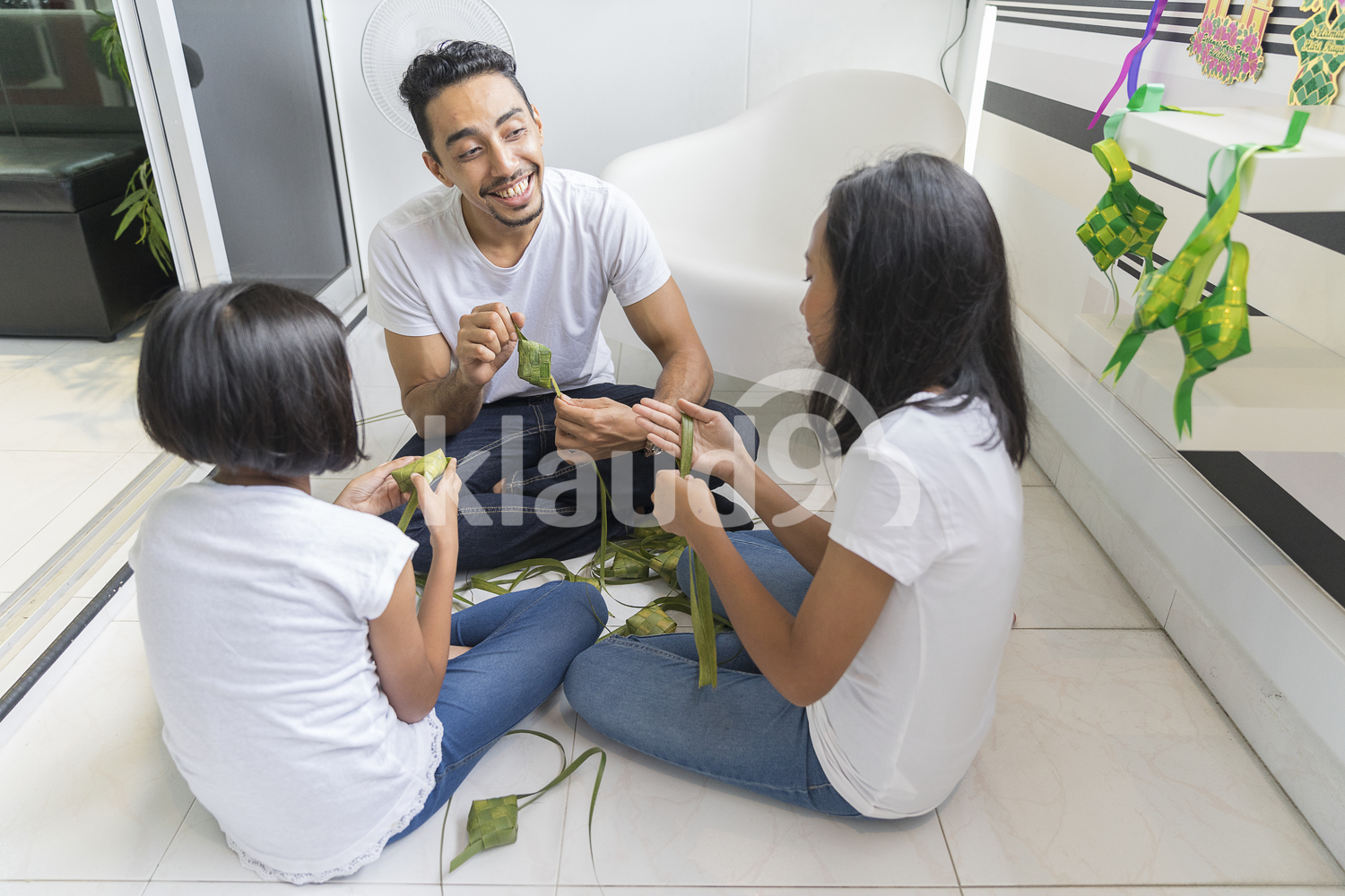 Father teaching his kids how to make ketupat