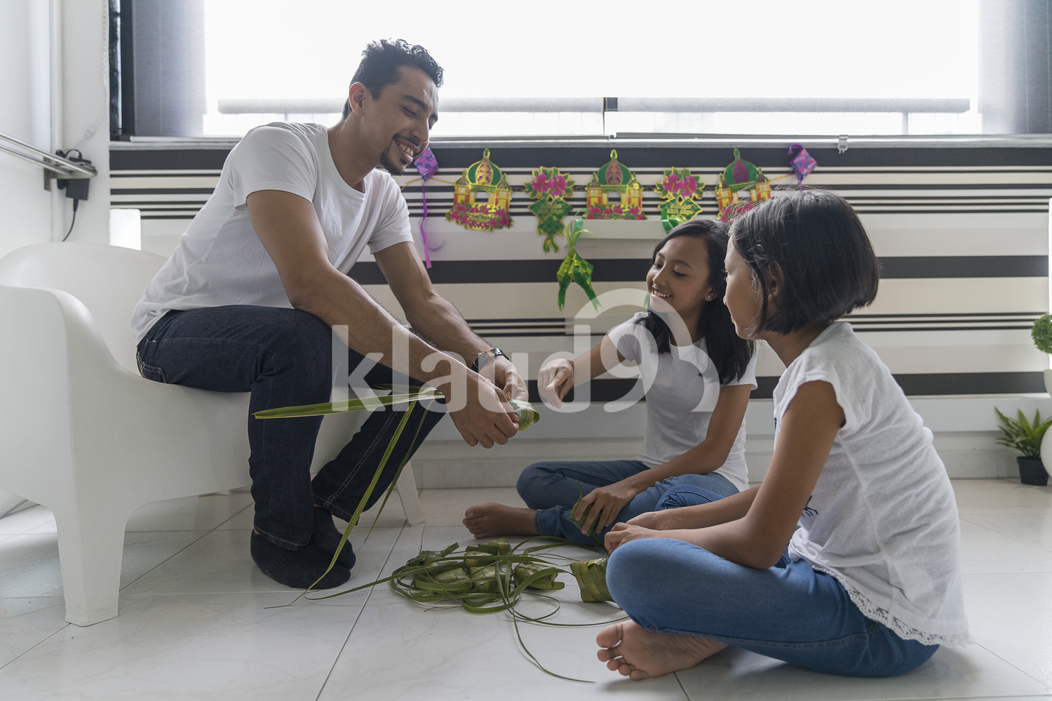 Father teaching his kids how to make ketupat for Hari Raya