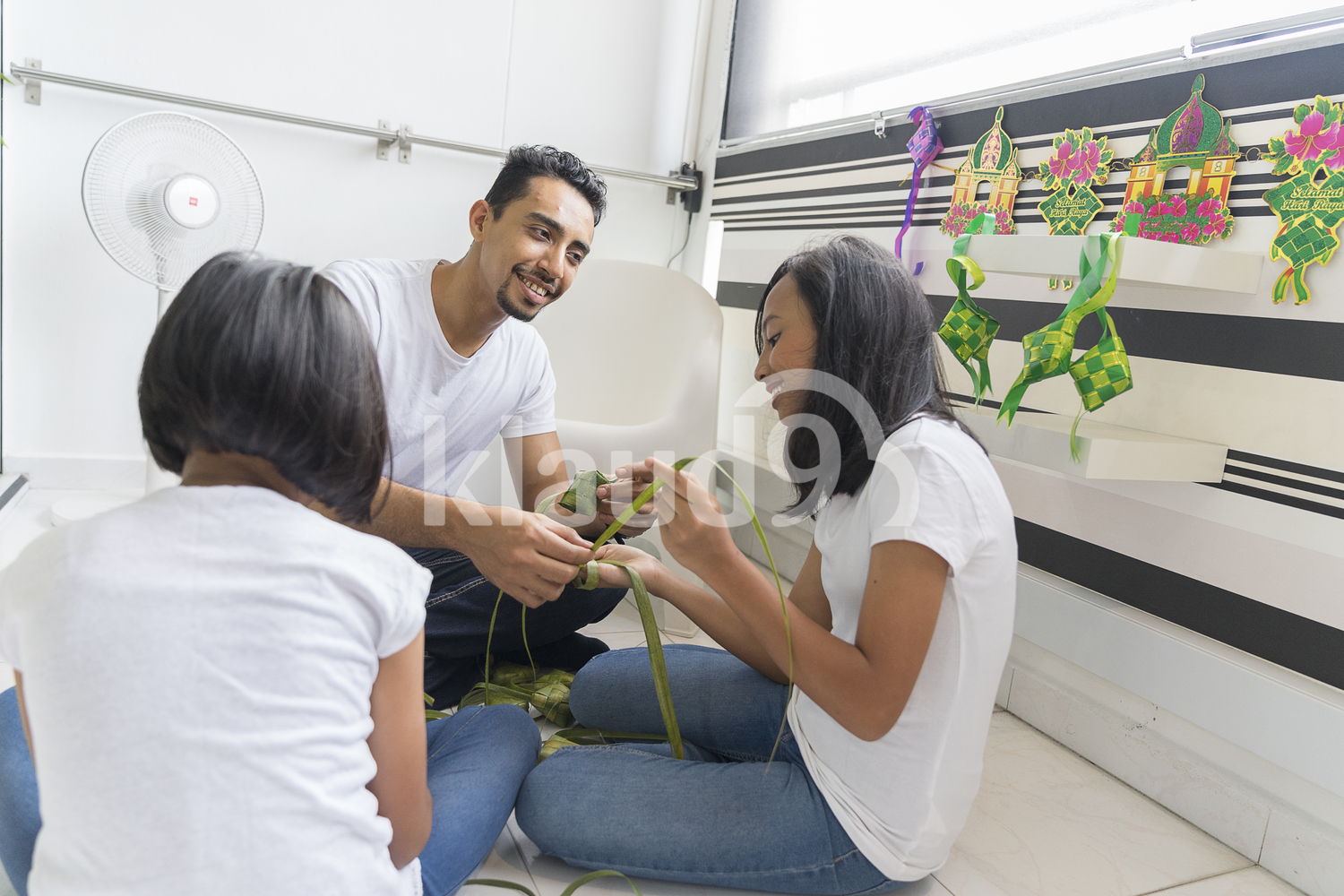 Father teaching his kids how to make ketupat.