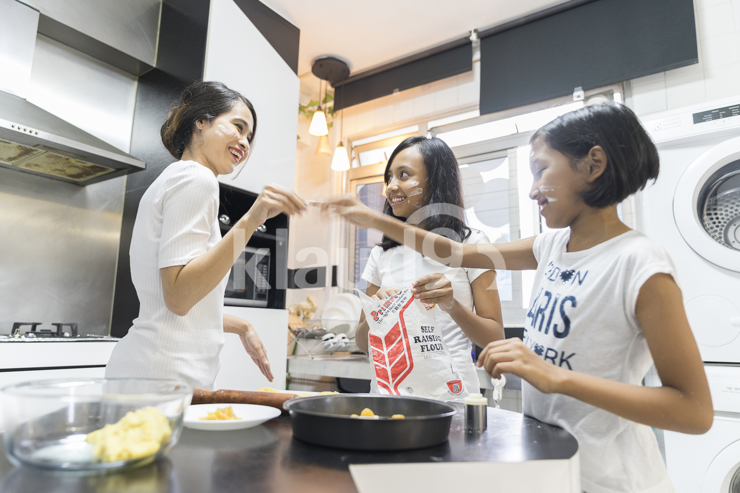 Mother and her daughters having fun during baking for Hari Raya