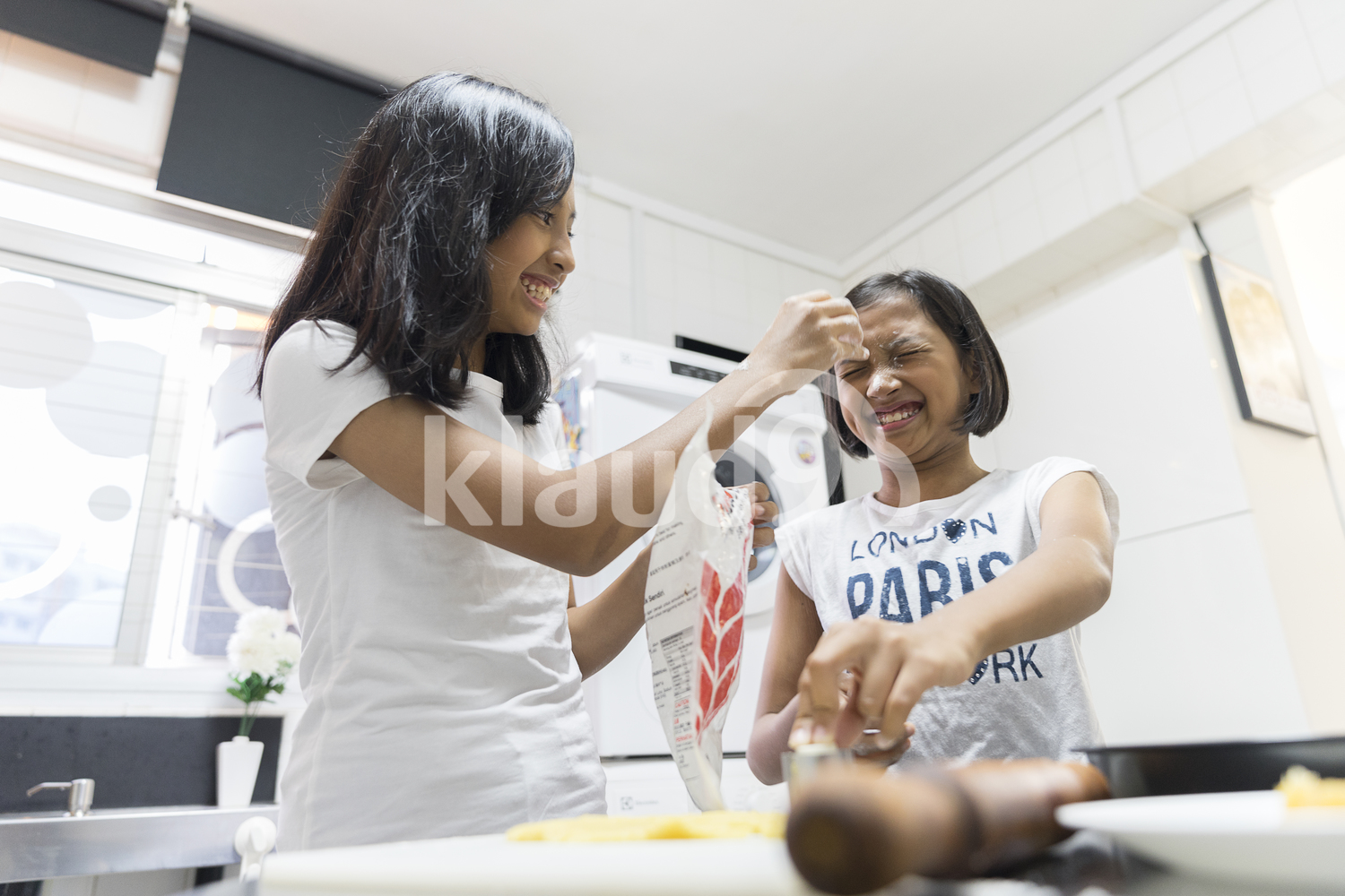 Sisters playing with flour in the kitchen
