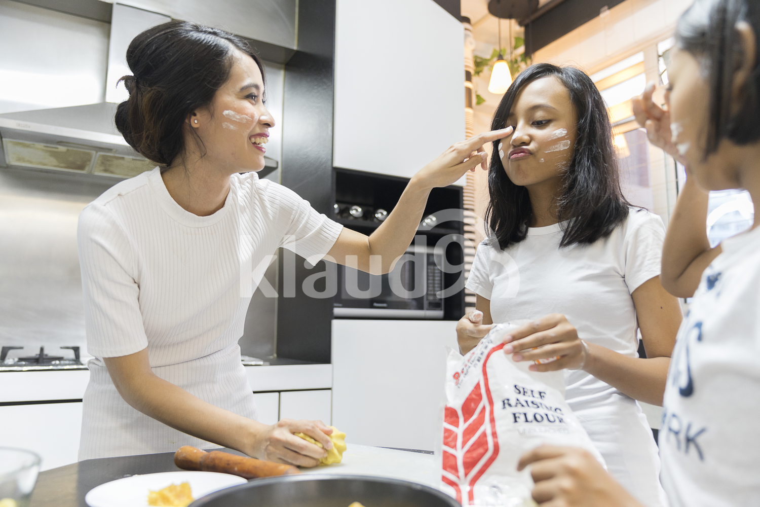 Mother putting flour on her daughter's nose