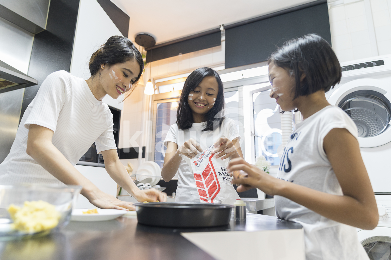 Mother and her daughters having fun during baking for Hari Raya