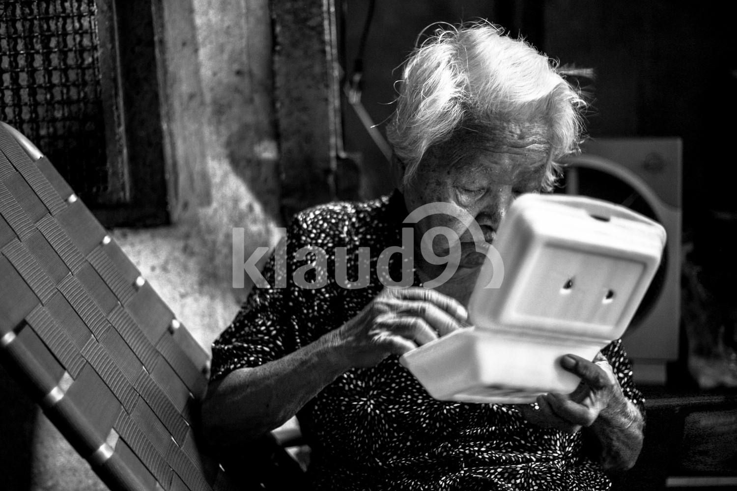 Old woman in Vietnam eating off a styrofoam box