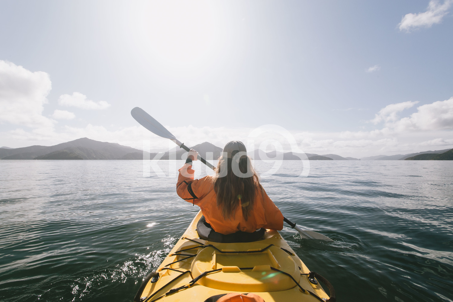 Back view of young woman kayaking at Milford Sound, New Zealand