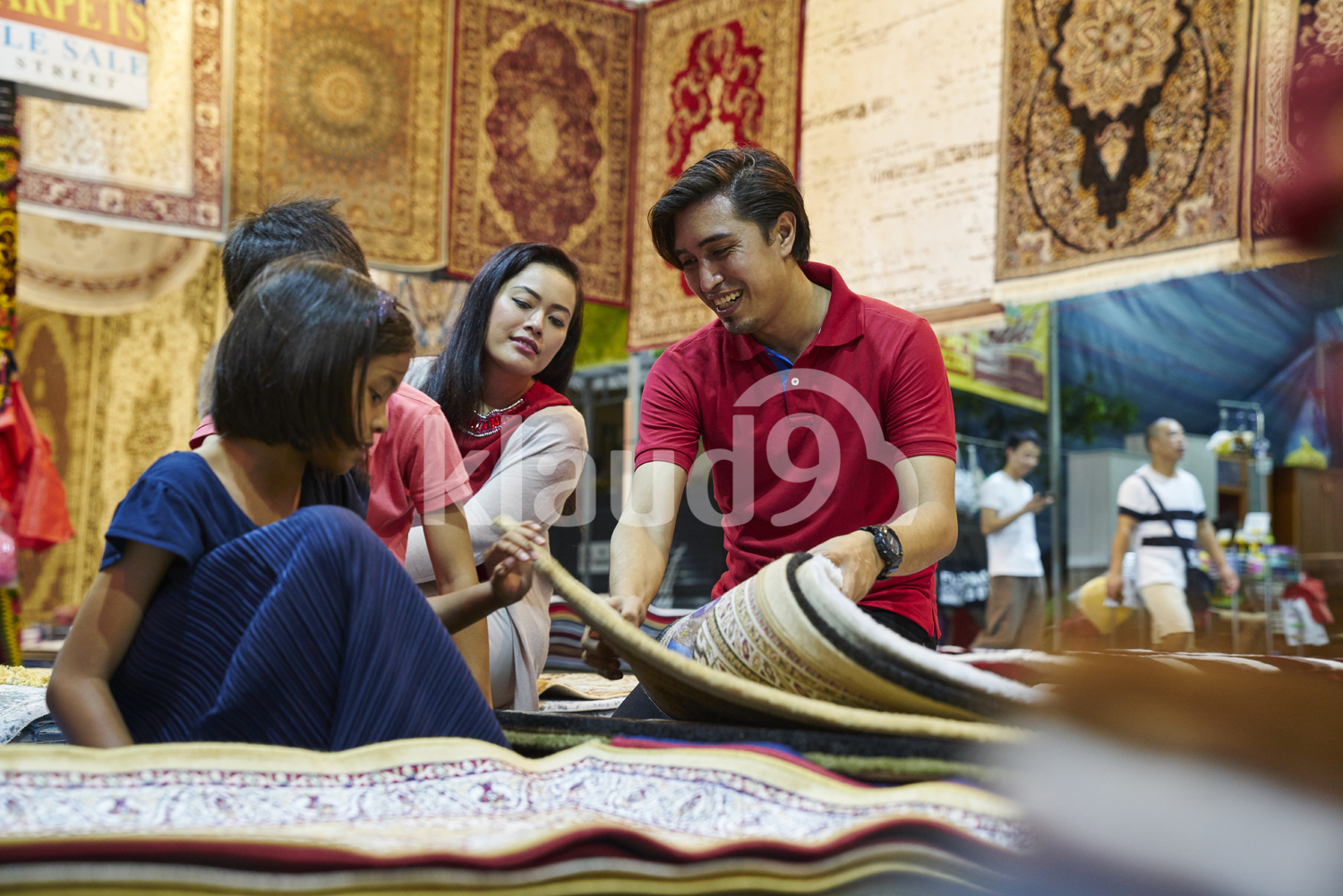 Young family browsing for carpets at Geylang Bazaar, Singapore