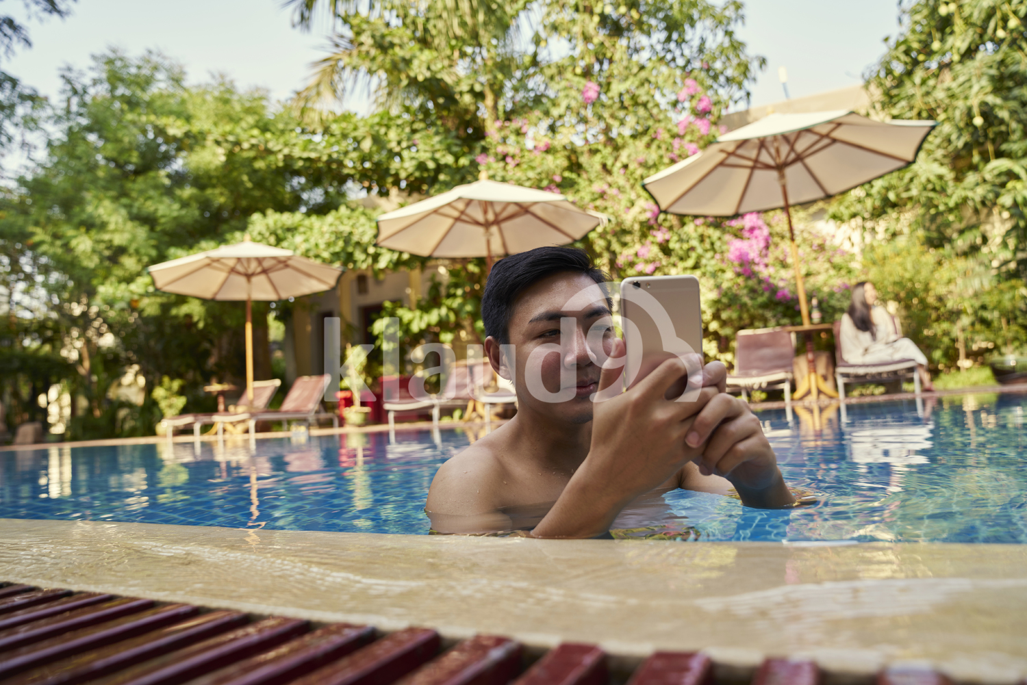 Young man taking photos with his mobile phone in the pool