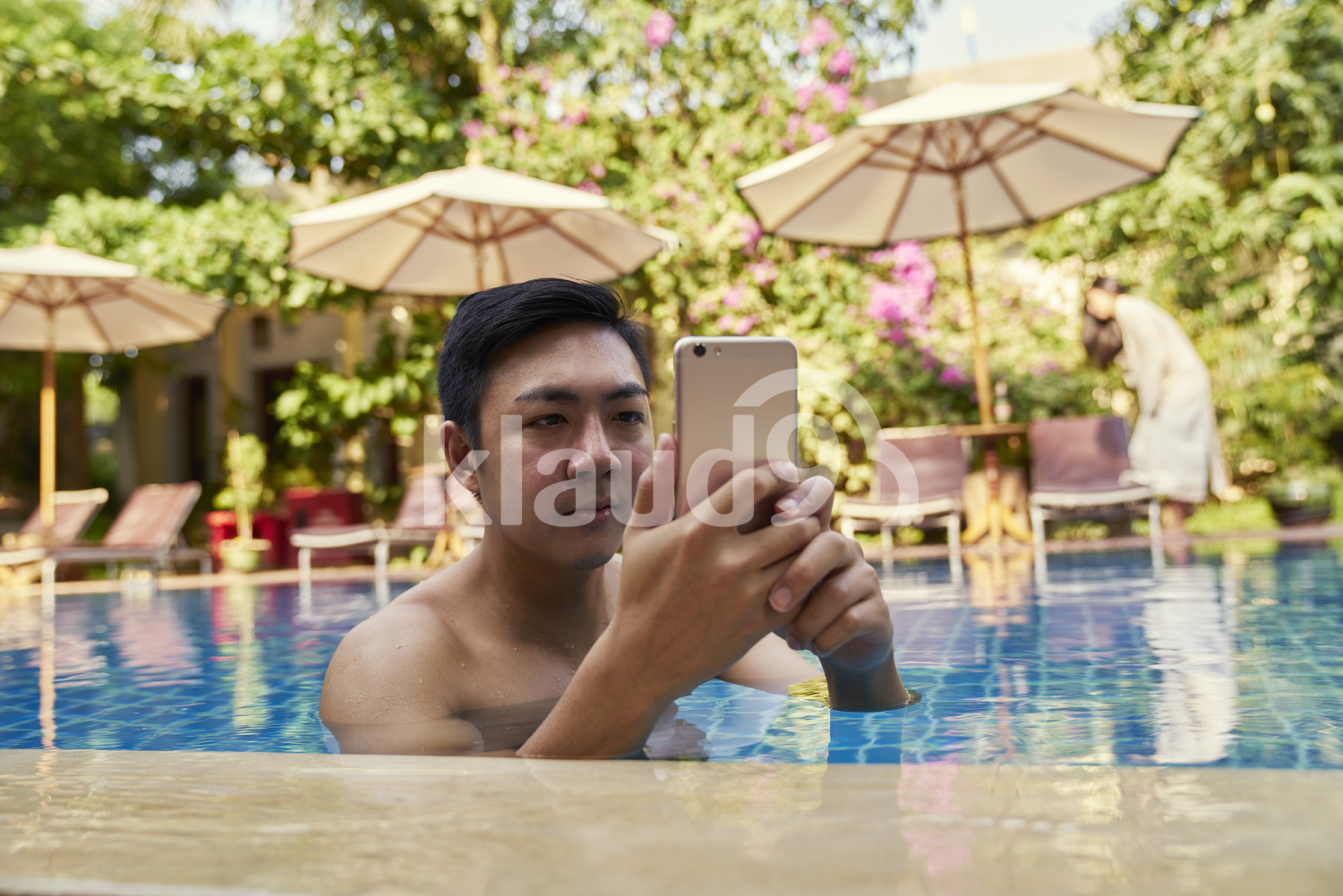 Young man taking photos with his mobile phone in the pool