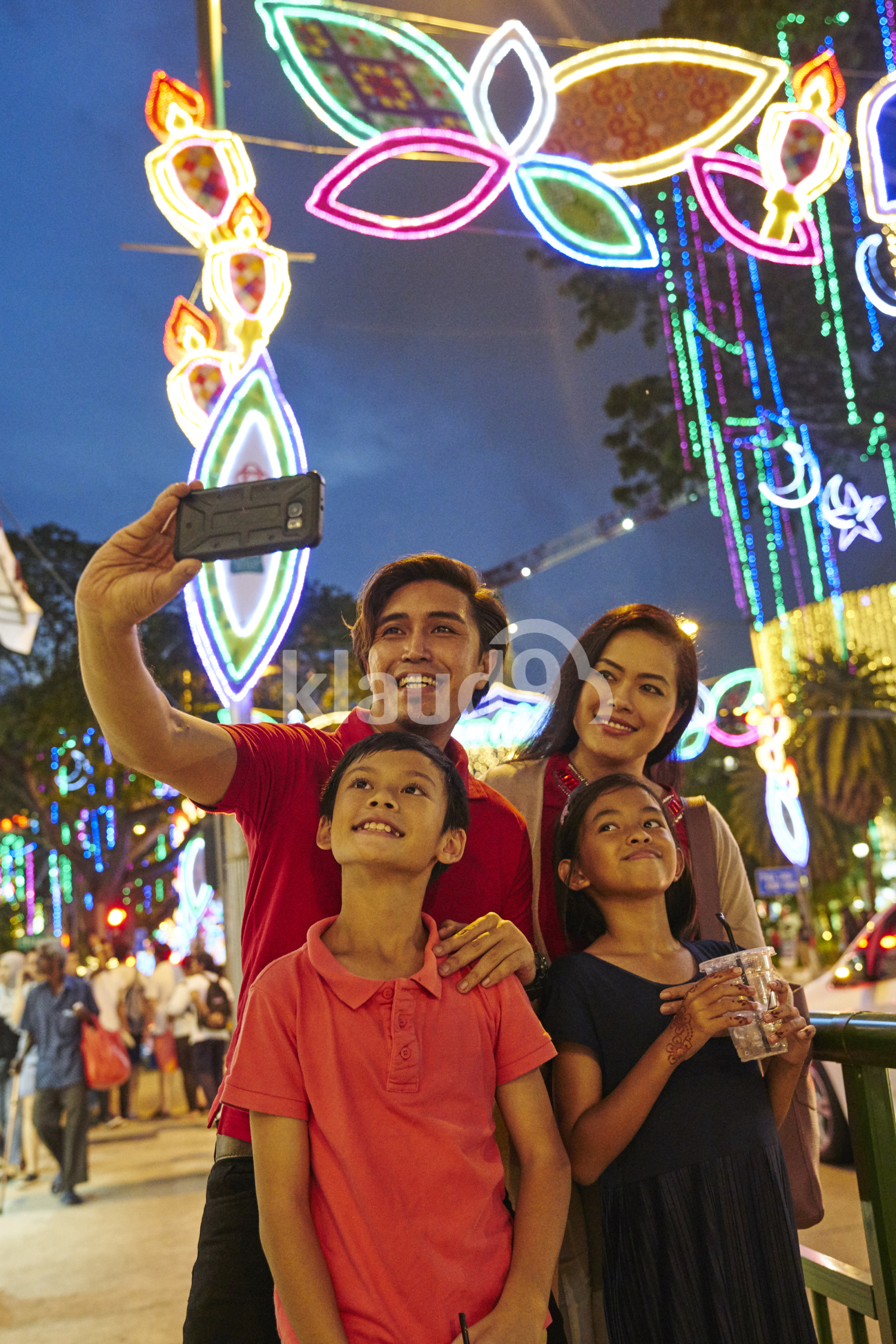 Smiling family taking selfies at Hari Raya Geylang Bazaar, Singapore