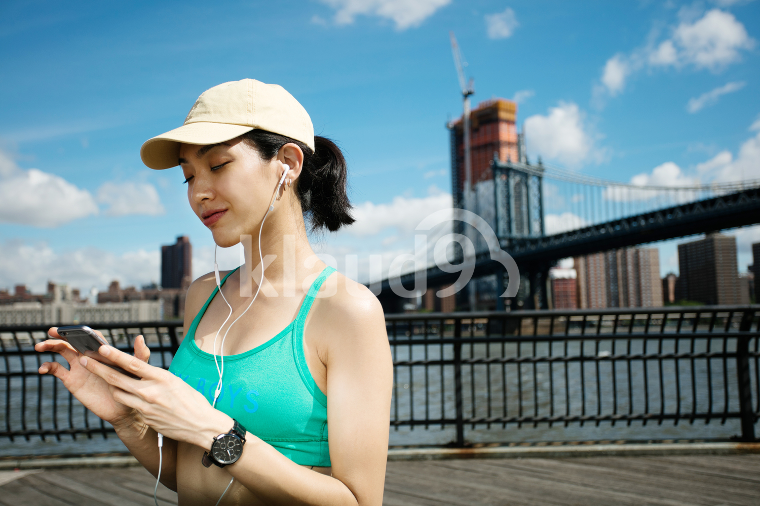 Pretty asian runner girl training outdoors working out at Brooklyn bridge with Manhattan, New York City in the background.