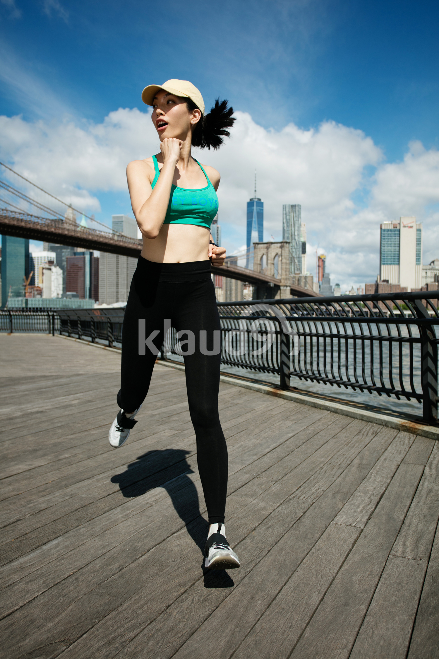 Pretty asian runner girl training outdoors working out at Brooklyn bridge with Manhattan, New York City in the background.
