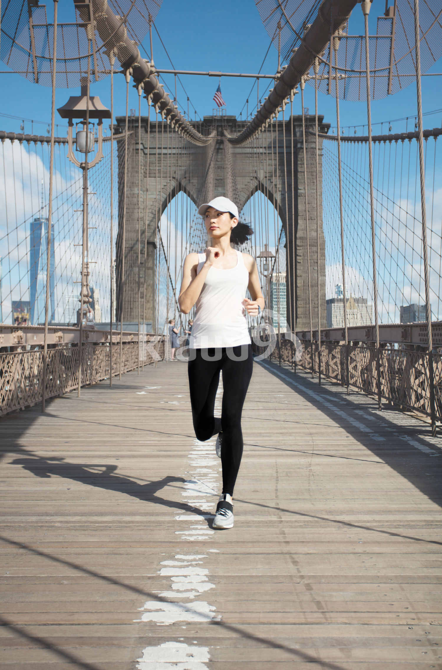 Pretty asian runner girl training outdoors working out at Brooklyn bridge with Manhattan, New York City in the background.