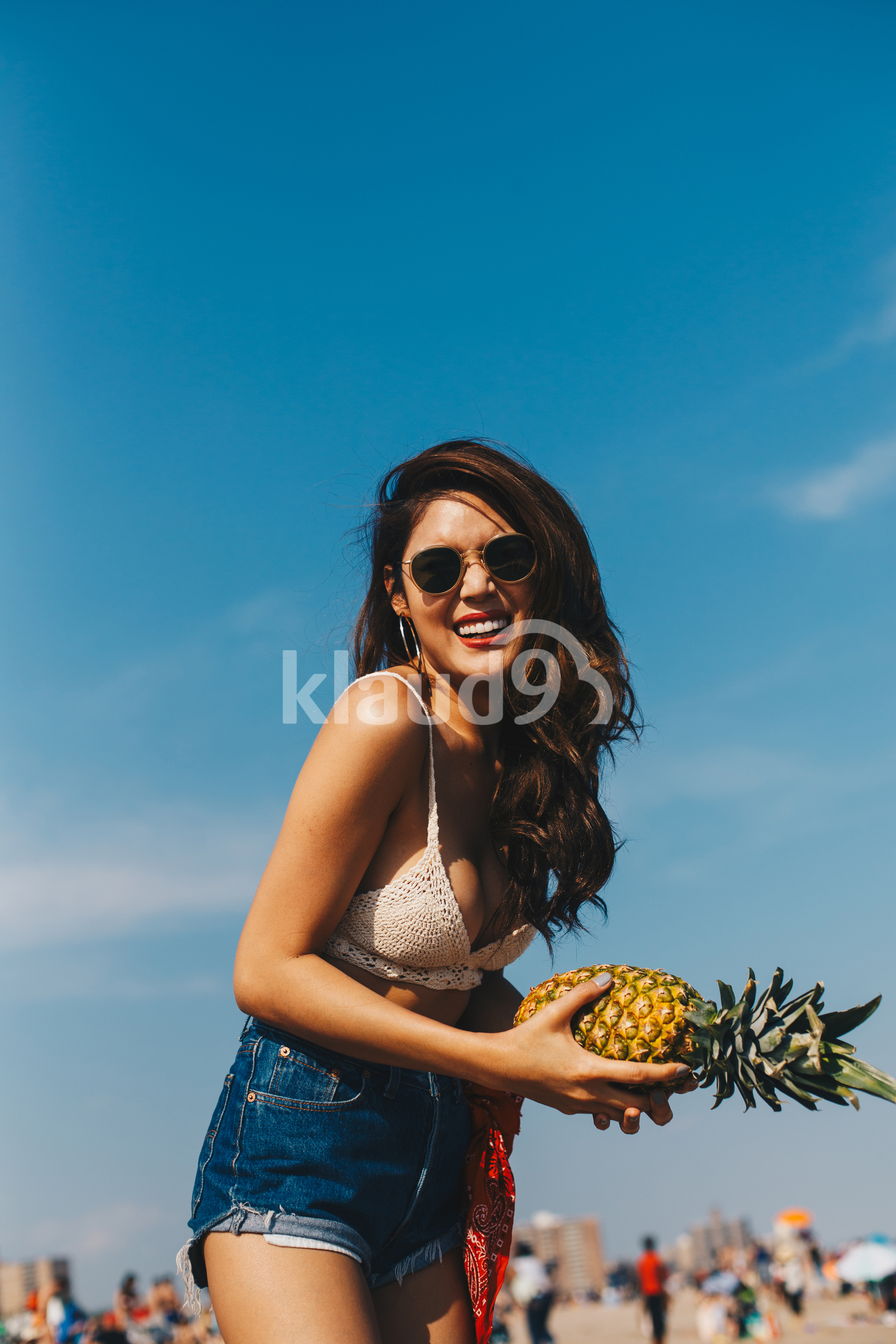 A beautiful girl holding the pineapple and having fun on the beach