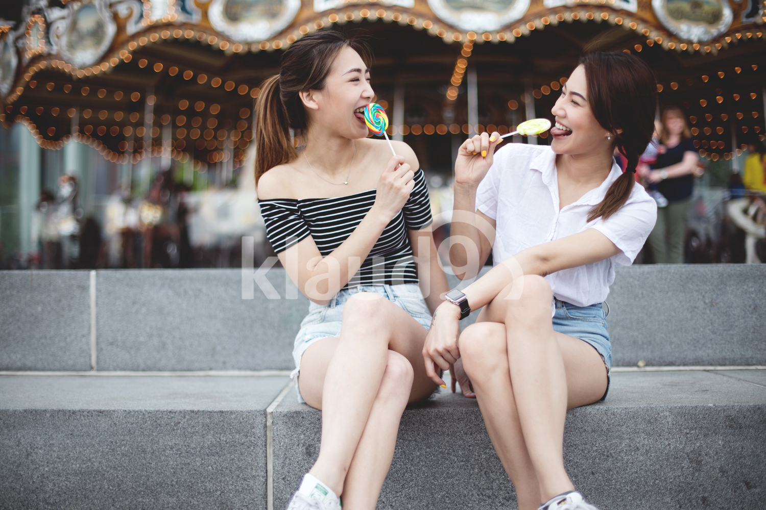 Teen asians girlfriends with candy having fun in the park