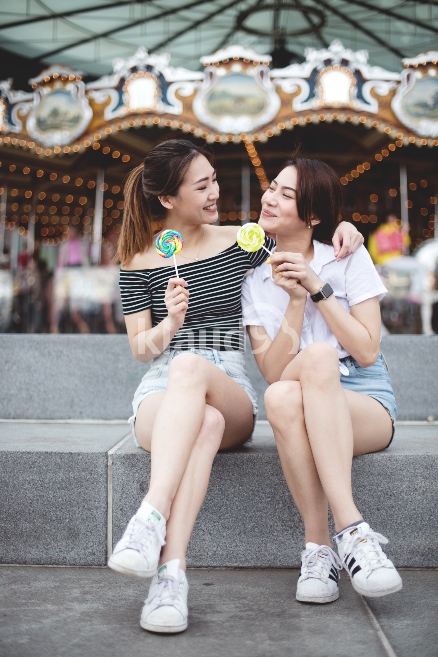 Teen asians girlfriends with candy having fun in the park