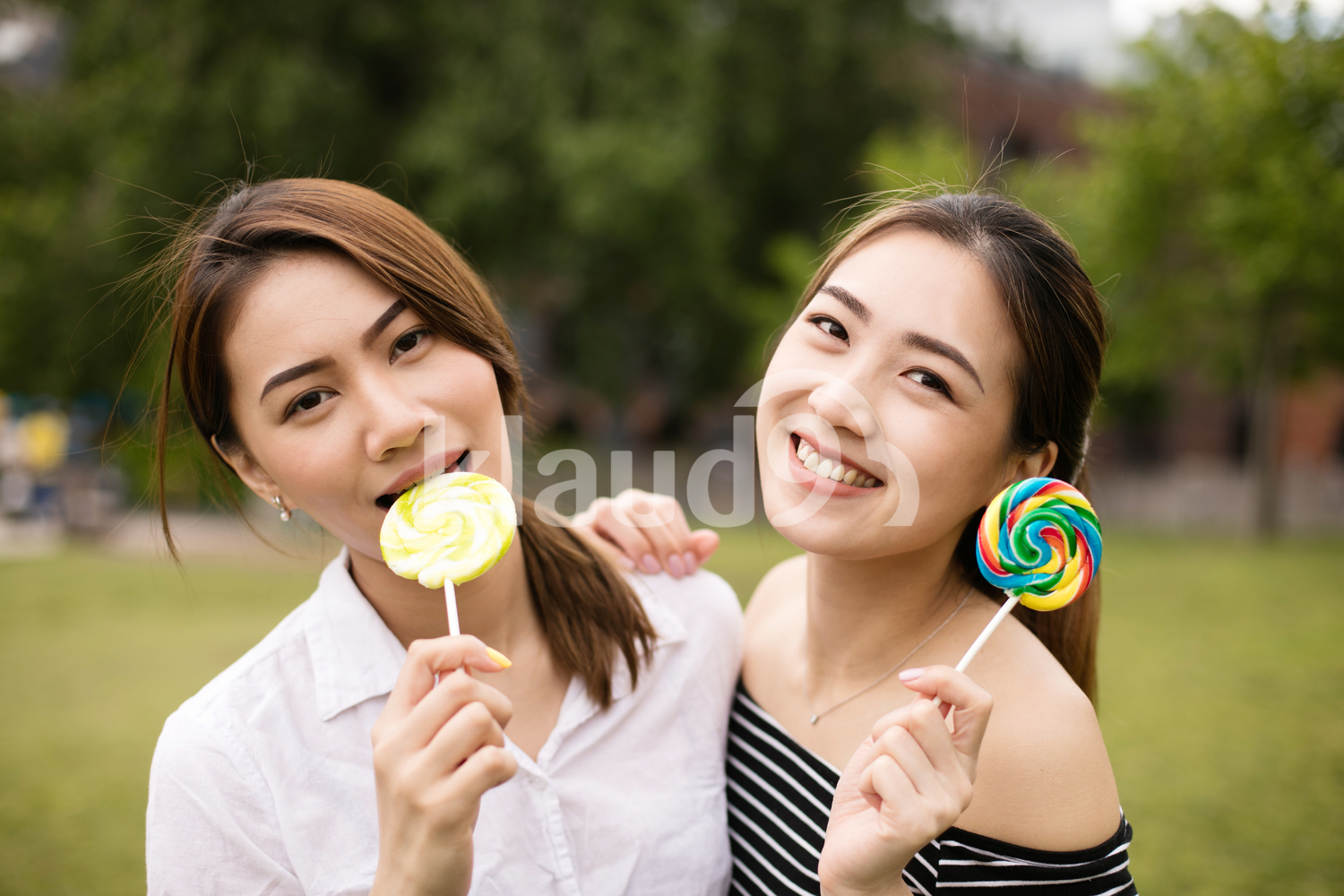 Teen asians girlfriends with candy having fun in the park