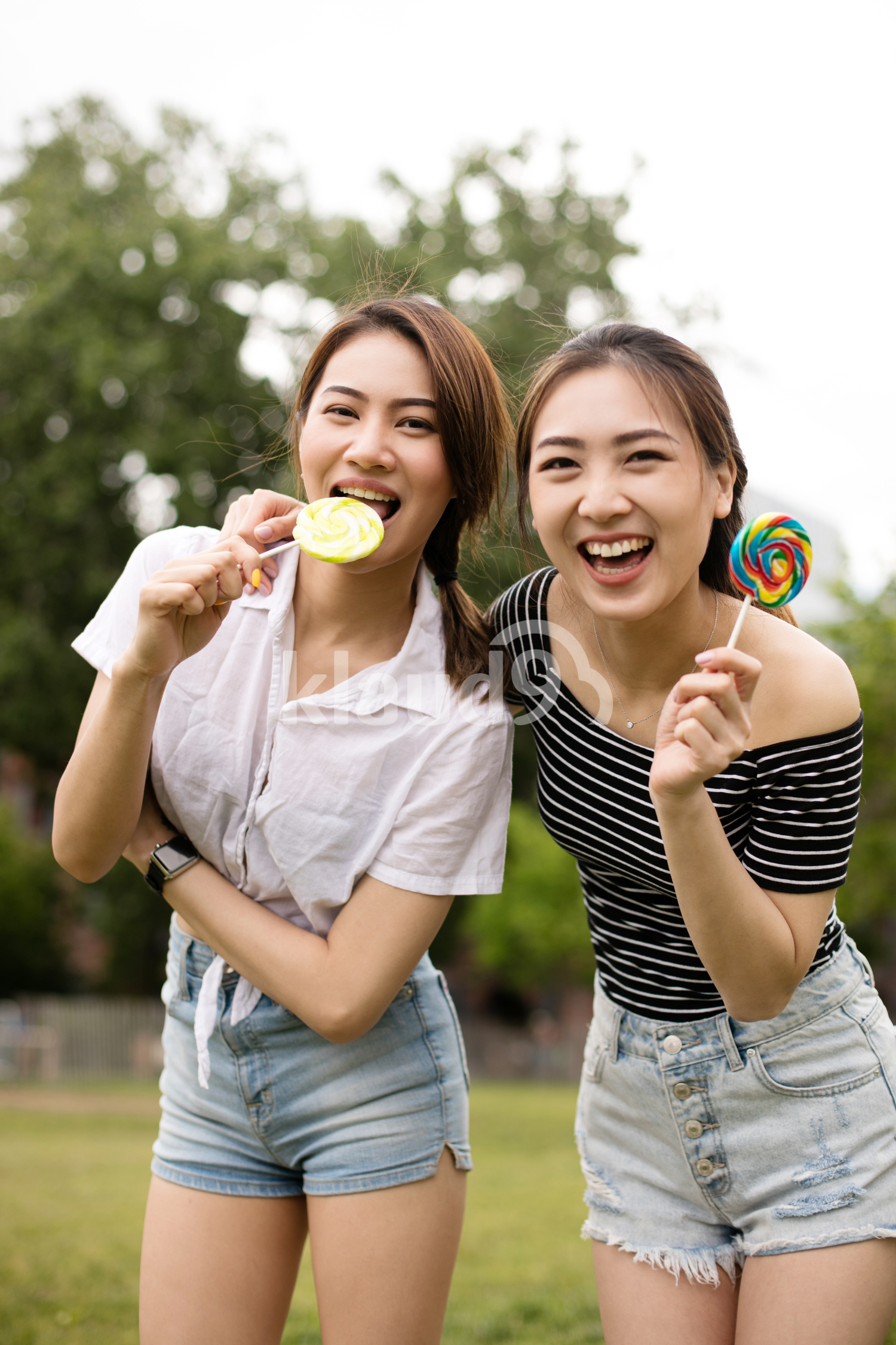 Teen asians girlfriends with candy having fun in the park