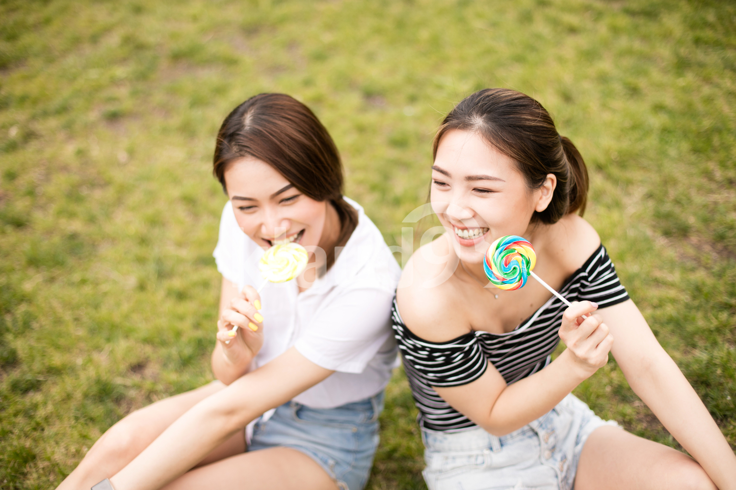 Teen asians girlfriends with candy having fun in the park