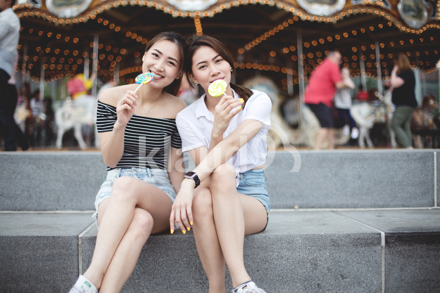 Teen asians girlfriends with candy having fun in the park