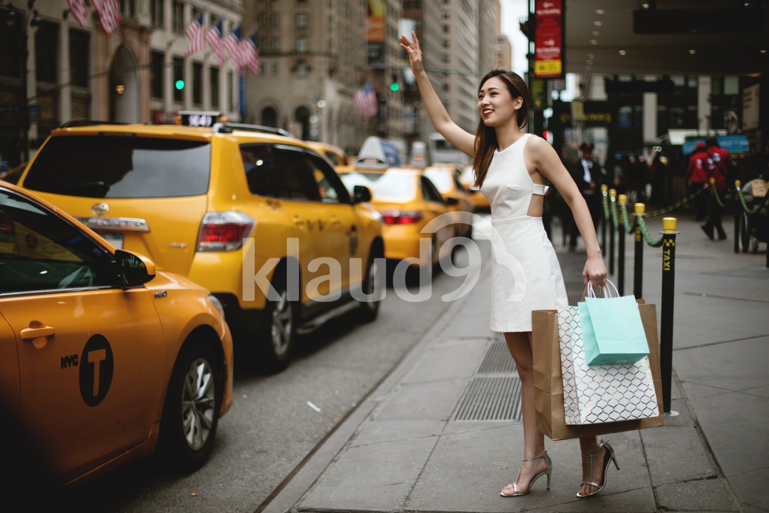 Young woman hailing a yellow cab in the city after her big shopping.