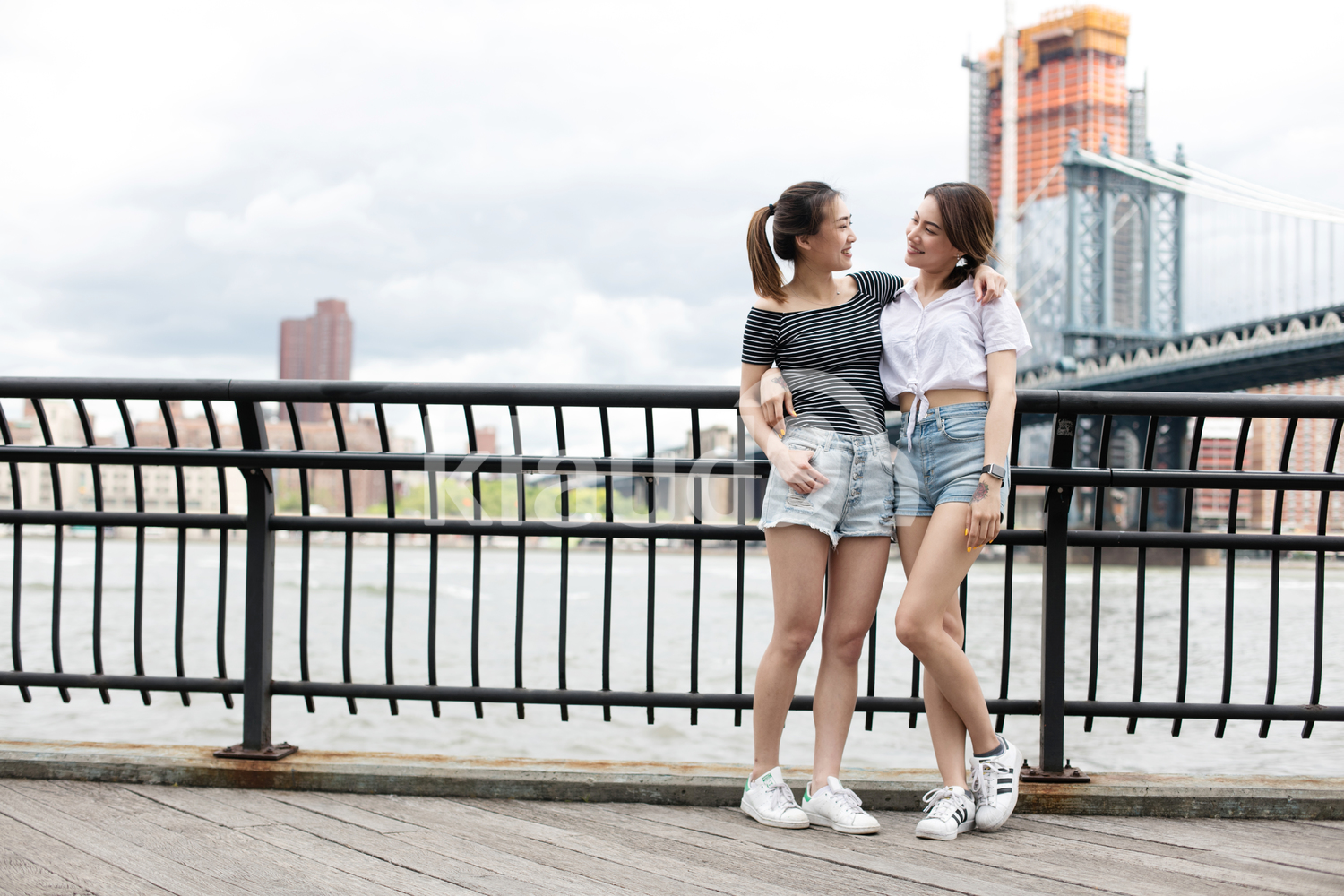Asian girlfriends hanging out with the Brooklyn Bridge in the background when is summer.