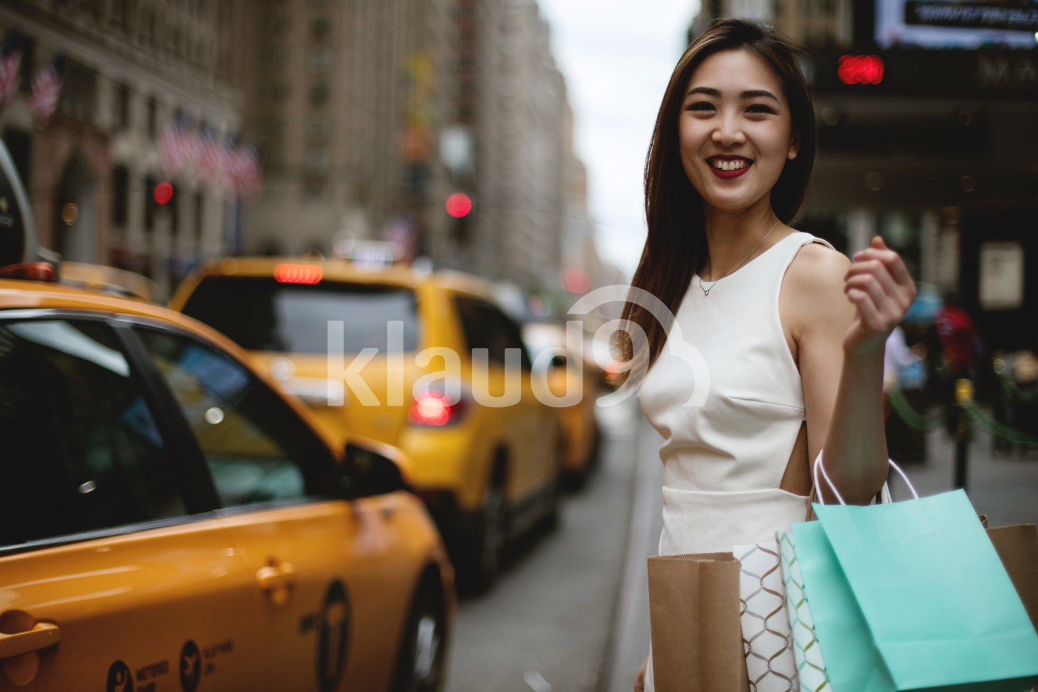 Young woman hailing a yellow cab in the city after her big shopping.