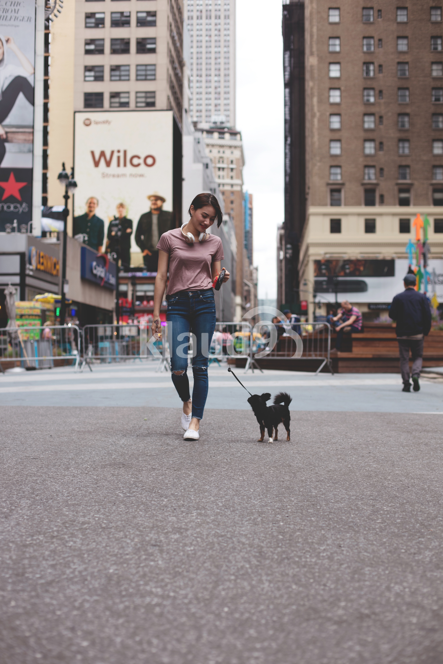Beautiful Woman walking her dogs through the city with empire state behind.